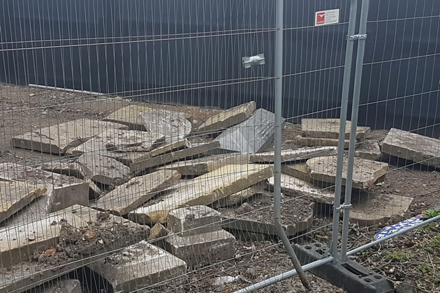 Gravestones piled by the perimeter fence by St Lawrence's Church