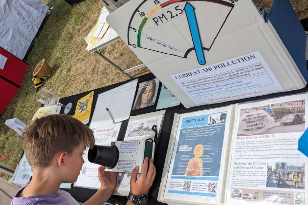 A young visitor to Ealing Friends of the Earth&rsquo;s stall, takes a reading from the PM2.5 meter